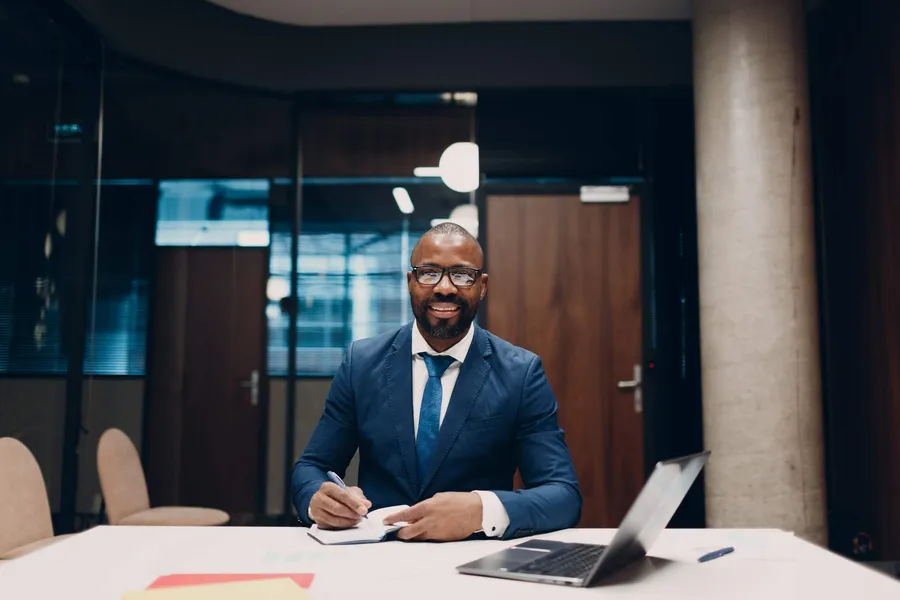 African manager taking notes during an AI strategy session with laptop and notebook