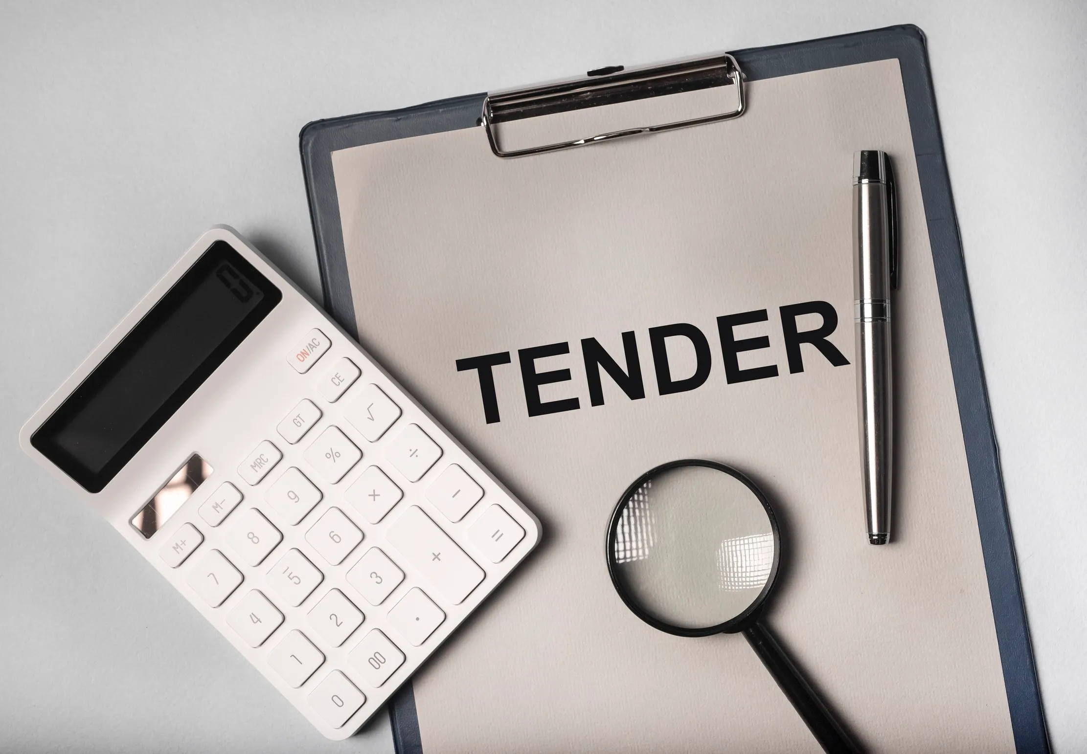 Tender document, calculator and magnifying glass representing institutional procurement readiness