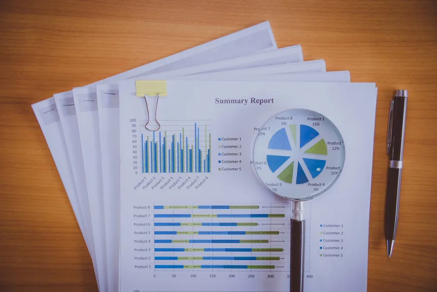 Magnifying glass examining a printed graph, representing a reviewer tracing a number back to its source