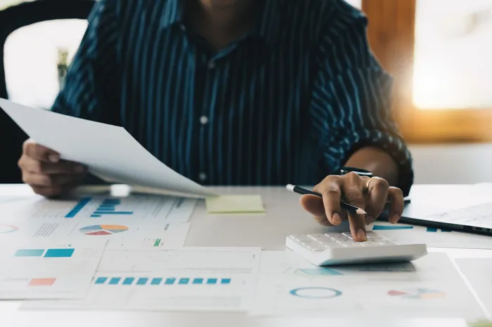 Finance manager checking figures against supporting paperwork with a calculator, representing audit-ready reporting