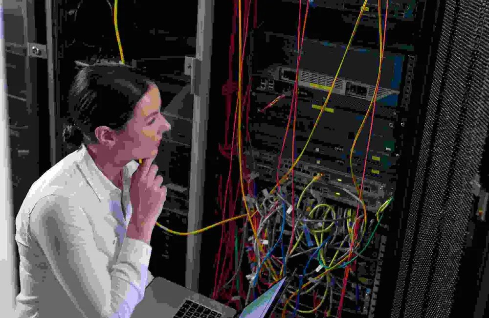 IT administrator reviewing a server rack with a laptop, representing Windows server administration