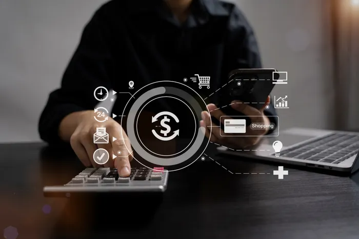 Business owner calculating the investment cost of a system on a calculator and phone, representing total cost of ownership