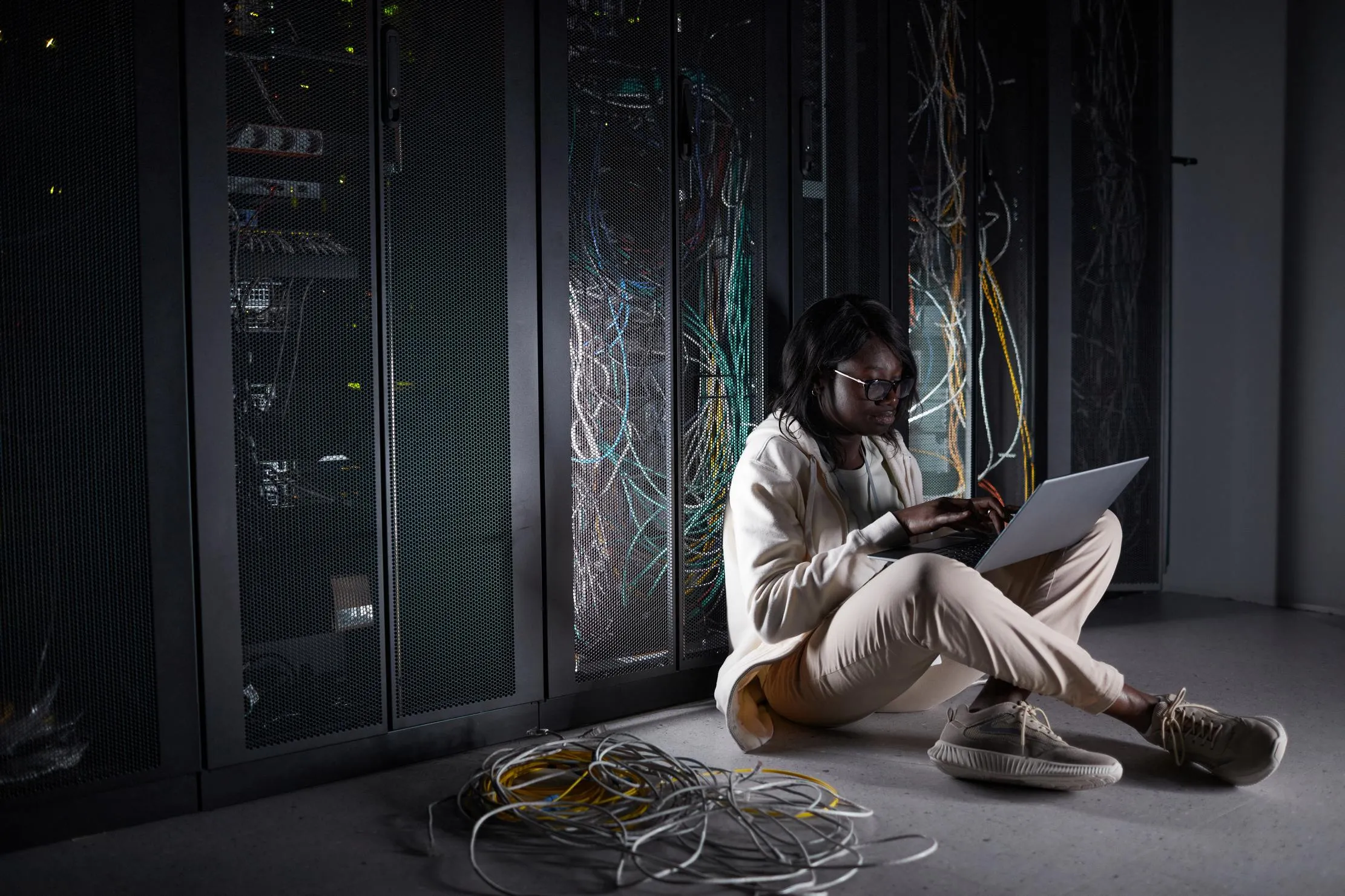 Woman using a laptop beside server racks, representing a digital service designed for constrained connectivity