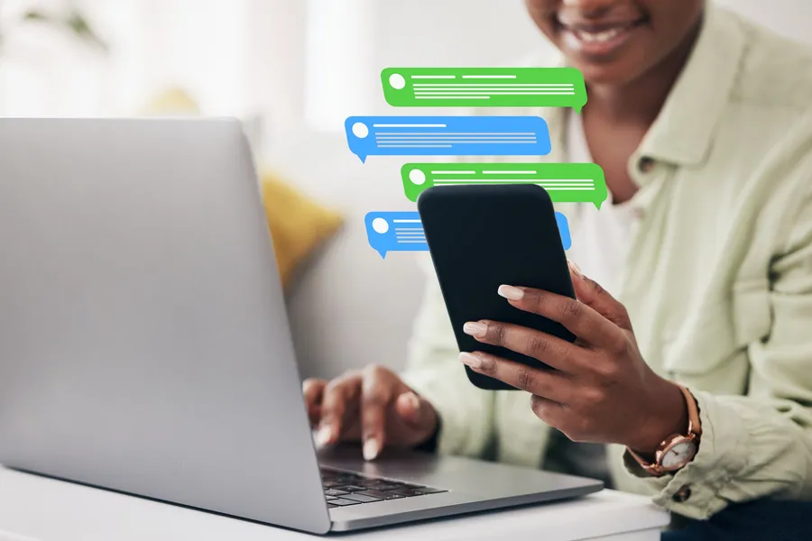 Person using phone and laptop for remote customer communication, representing human handoff from a WhatsApp AI assistant